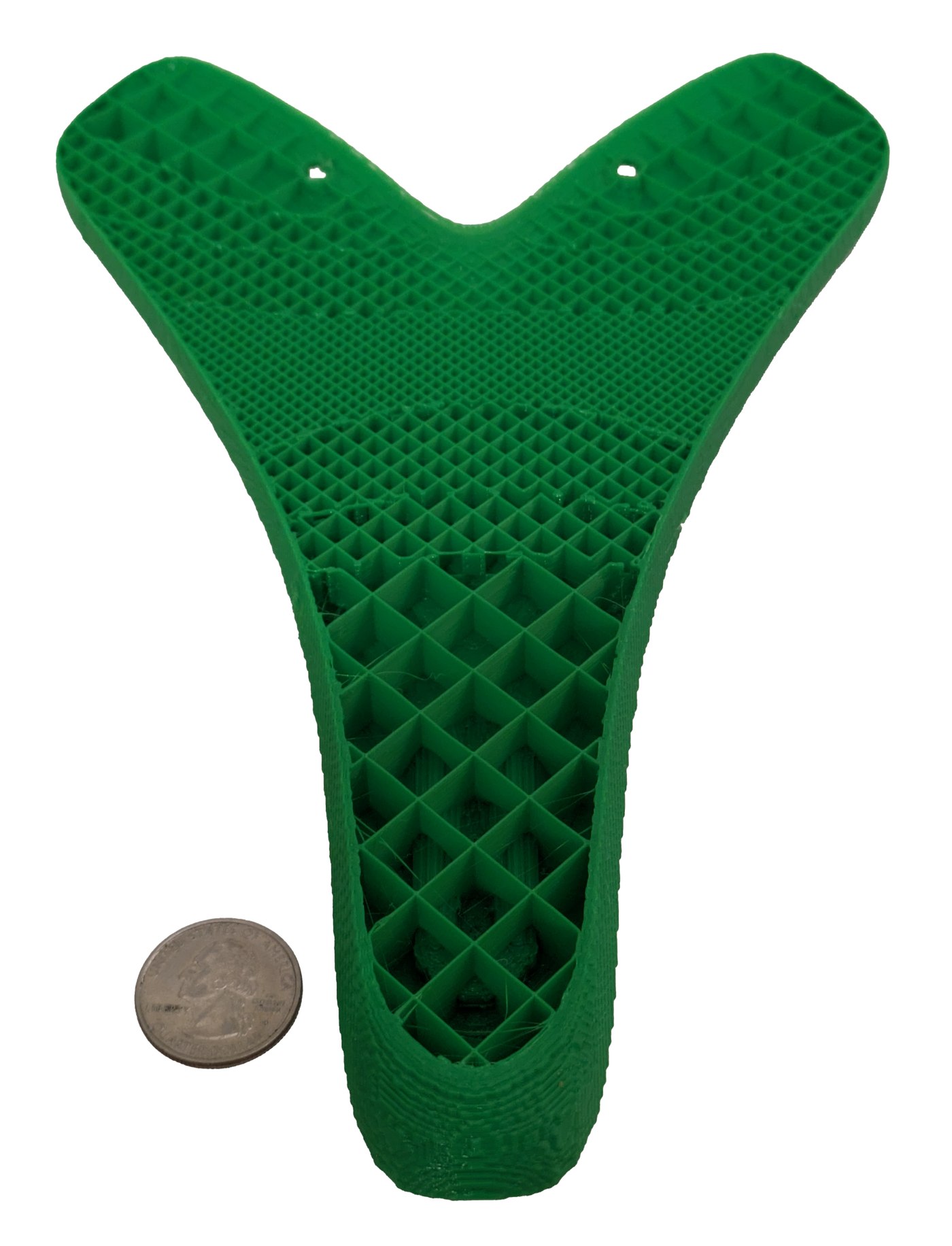 Green printed seat cut open, showing a lattice-like infill that is denser in some regions, beside a coin.